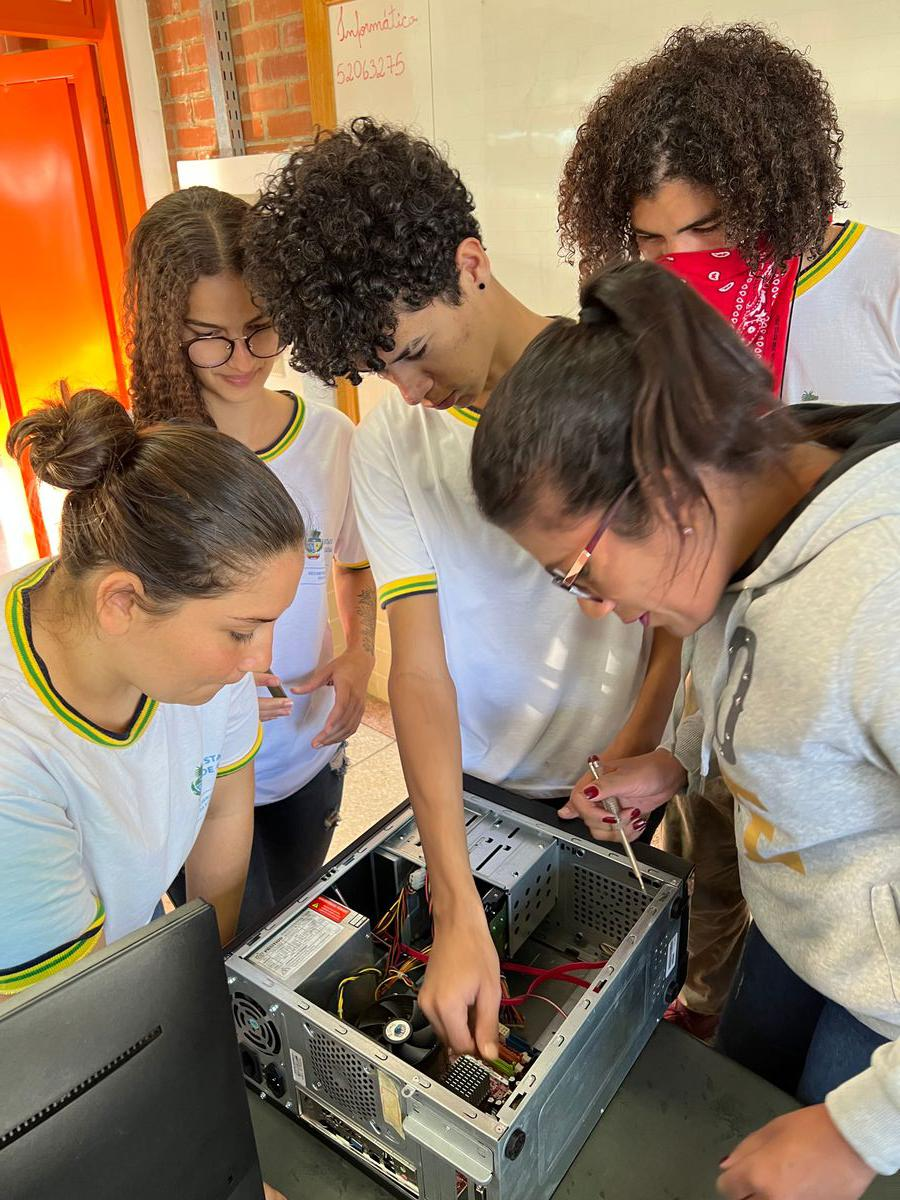 Estudantes concentrados manuseando ferramentas para conserto de uma CPU de computador.